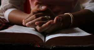 image of a person placing their hand on the bible reflecting on their journey from the life of loneliness to the new beginnings.