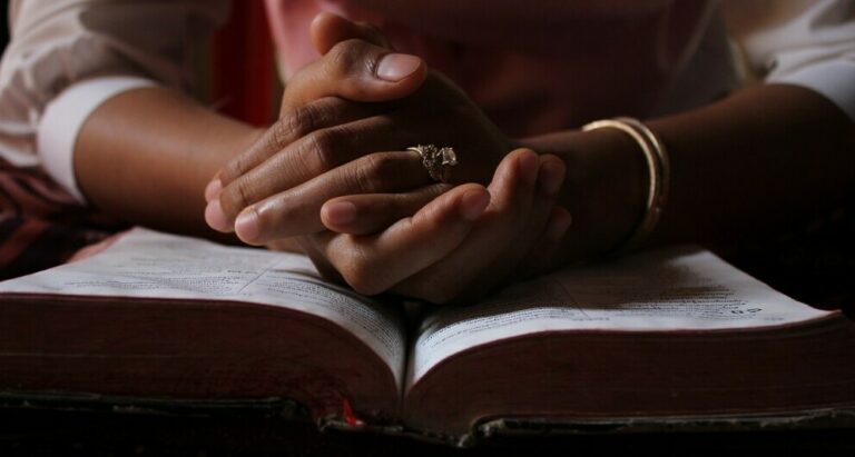 image of a person placing their hand on the bible reflecting on their journey from the life of loneliness to the new beginnings.