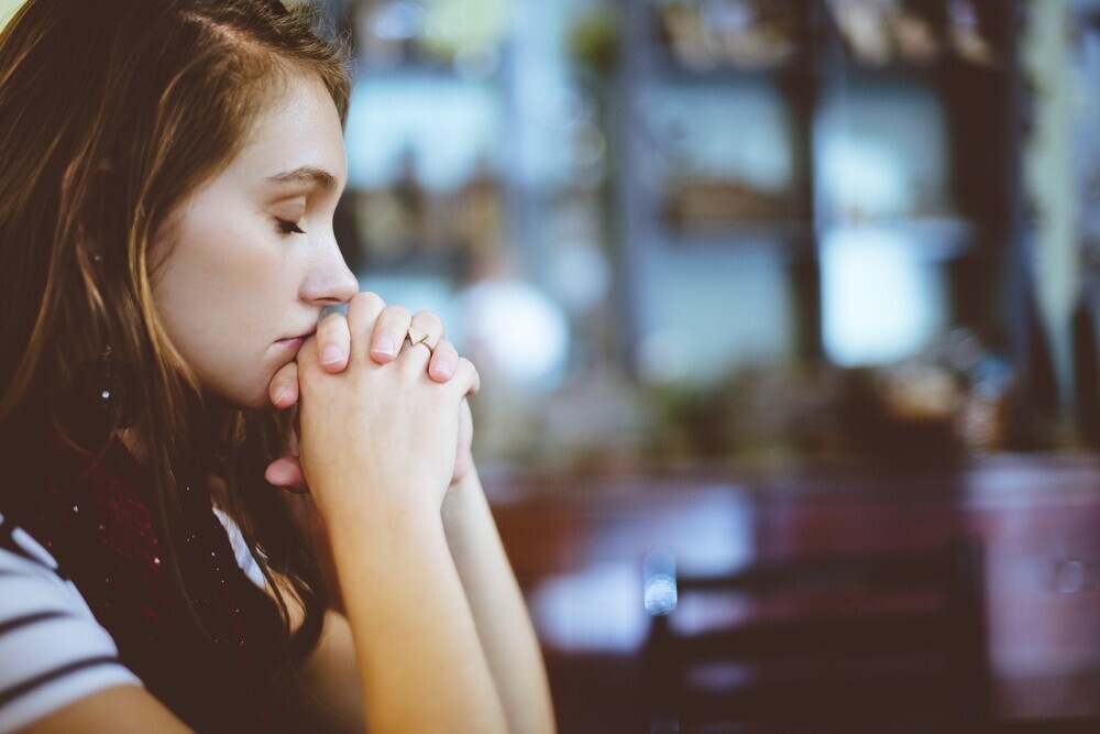 image of a beautiful woman praying and asking God to help her to overcome her loneliness and to find hope in despair.