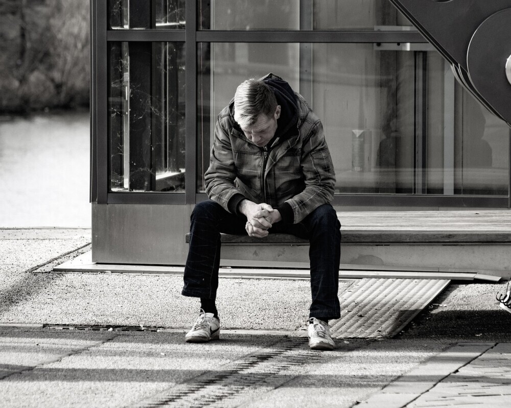 image of a man experience a life of loneliness at the front of his house.