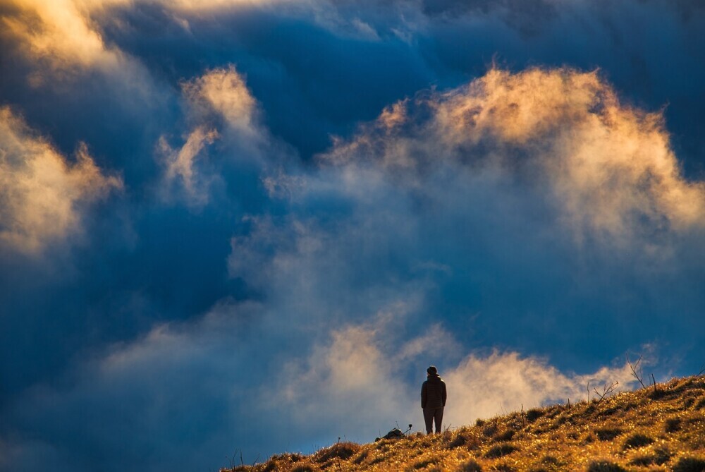 image of a man standing alone in the mountain enjoying God's presence filling his loneliness.